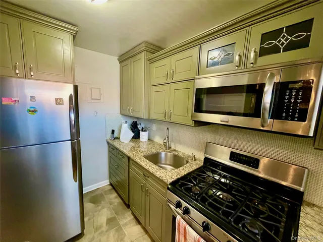 a kitchen with stainless steel appliances granite countertop a refrigerator and a stove top oven