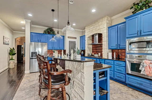 a kitchen with stainless steel appliances kitchen island granite countertop a kitchen island a stove a refrigerator a sink a table and chairs