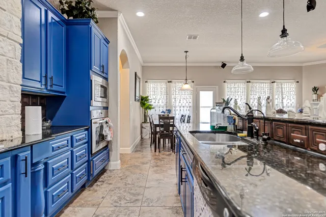 a kitchen with granite countertop a sink a counter space appliances and cabinets