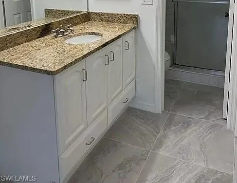 a bathroom with a granite countertop sink and washing machine
