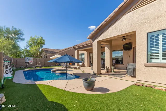 a backyard of a house with table and chairs plants and a barbeque