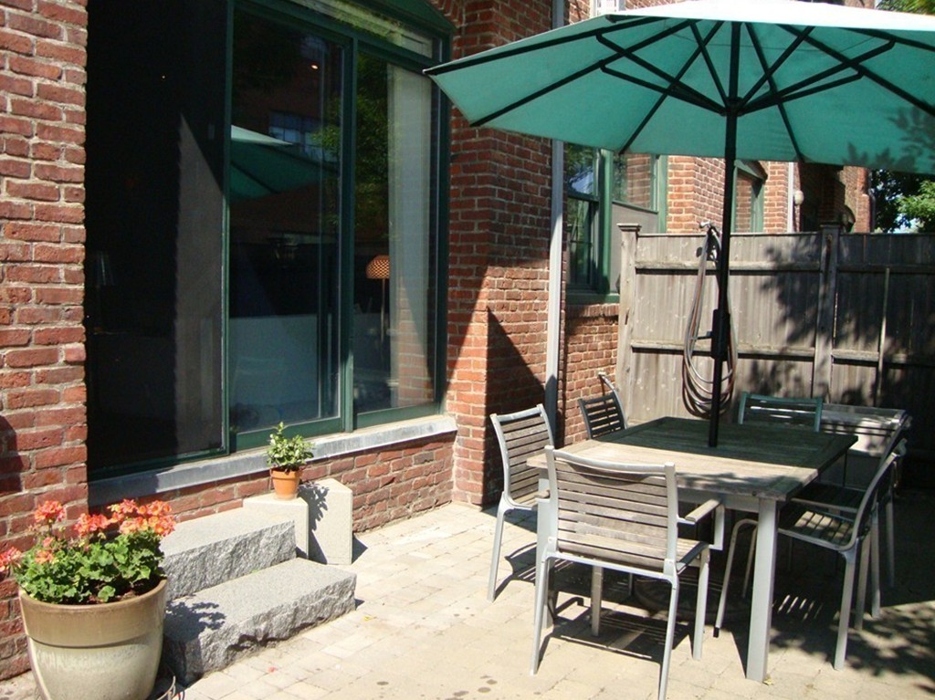 210 Broadway, Unit 104 Everett, MA 02149 - Photo 7 of 13 a view of a patio with table and chairs under an umbrella