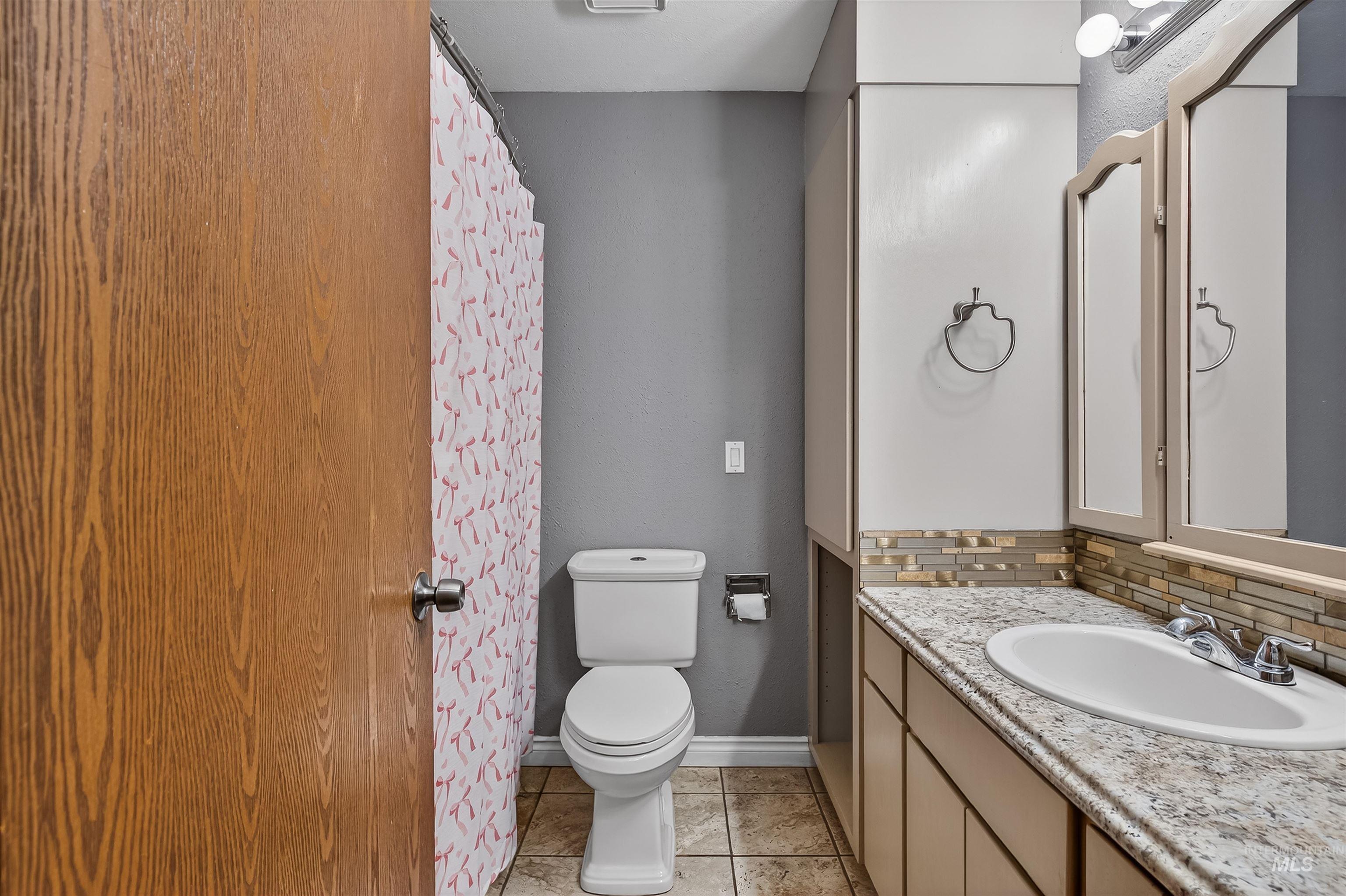 3725 11th Street Lewiston, ID 83501 - Photo 17 of 46 Full bathroom with vanity, a shower with curtain, decorative backsplash, and light tile patterned flooring