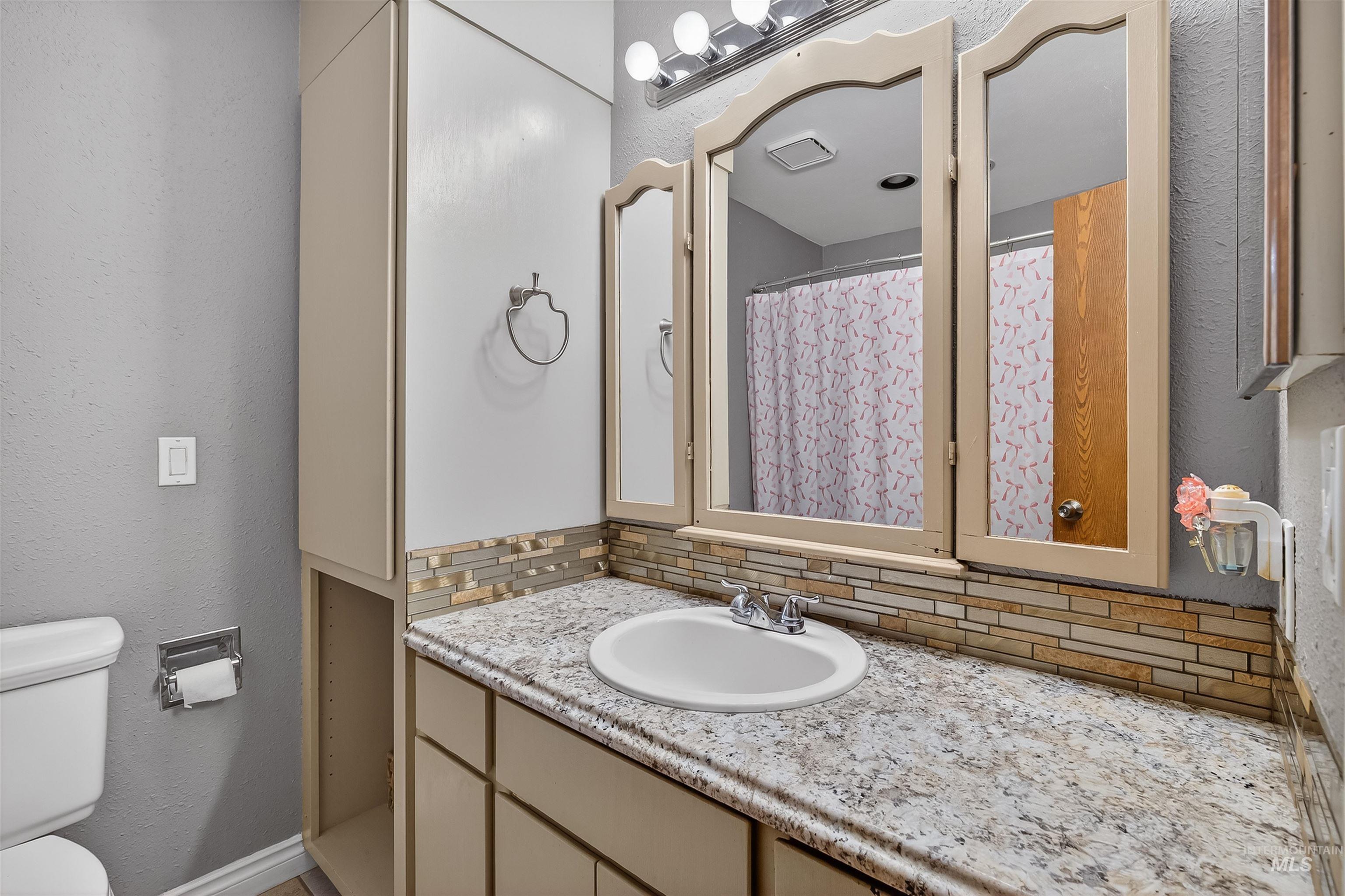 3725 11th Street Lewiston, ID 83501 - Photo 18 of 46 Full bath with backsplash, a textured wall, vanity, and curtained shower