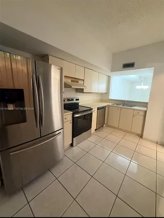 a kitchen with granite countertop a refrigerator and a stove top oven
