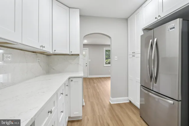 a kitchen with a refrigerator a sink and dishwasher with white cabinets