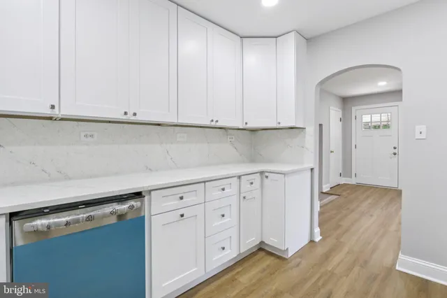 a kitchen with white cabinets and a stove with wooden floors