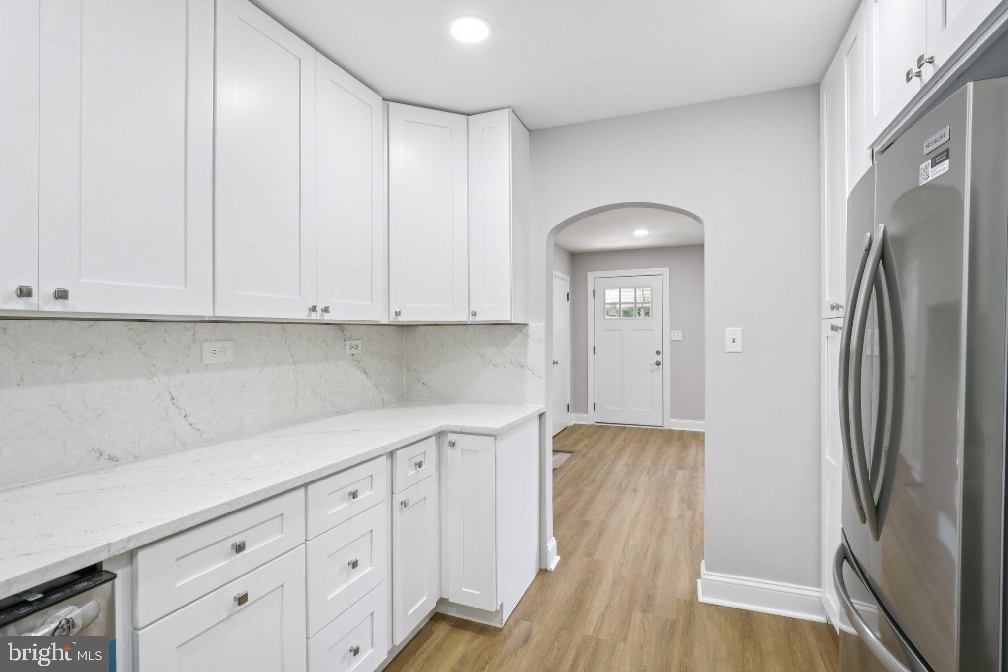 1 Russell Road New Castle, DE 19720 - Photo 23 of 49 a kitchen with stainless steel appliances granite countertop a refrigerator a sink and white cabinets with wooden floor