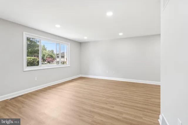 an empty room with wooden floor and window