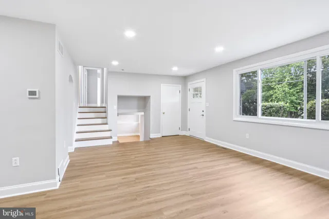 a view of empty room with wooden floor and window