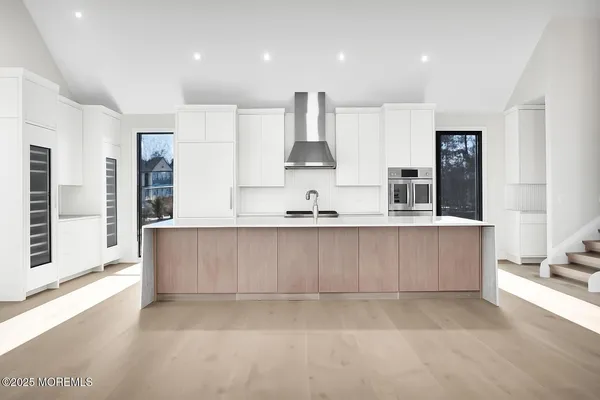 a view of kitchen with stainless steel appliances cabinets large window and wooden floor