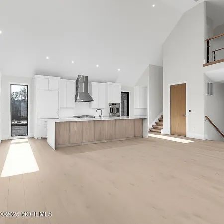 a large white kitchen with kitchen island a sink stainless steel appliances and cabinets