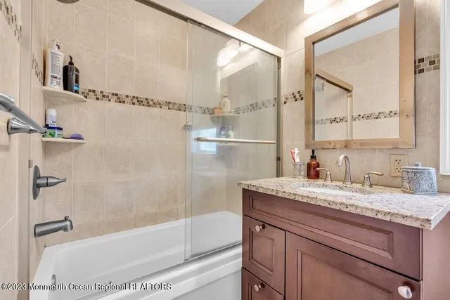 a bathroom with a granite countertop sink mirror vanity and bathtub