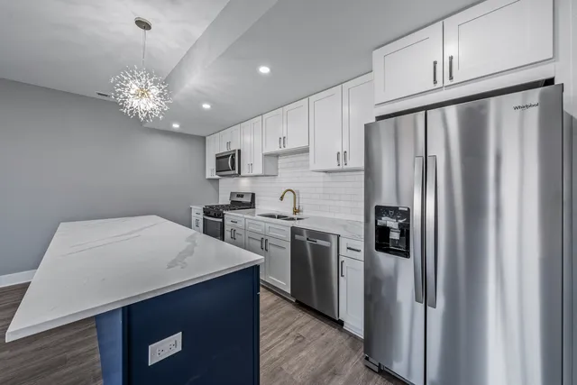 a kitchen with kitchen island a counter space a sink appliances and cabinets