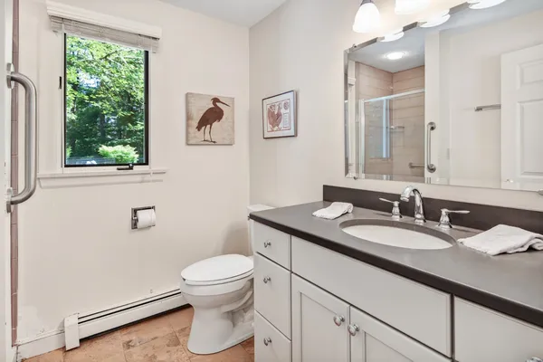 a bathroom with a granite countertop sink a toilet and a mirror