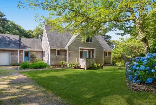 a front view of a house with a garden and trees