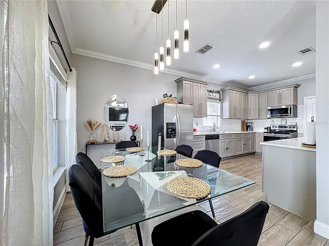 a kitchen with kitchen island granite countertop a sink a stove a dining table and chairs