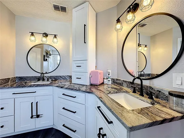a bathroom with a granite countertop double vanity sink and a mirror