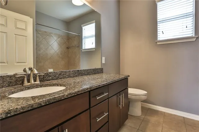 a bathroom with a granite countertop sink a toilet and a mirror