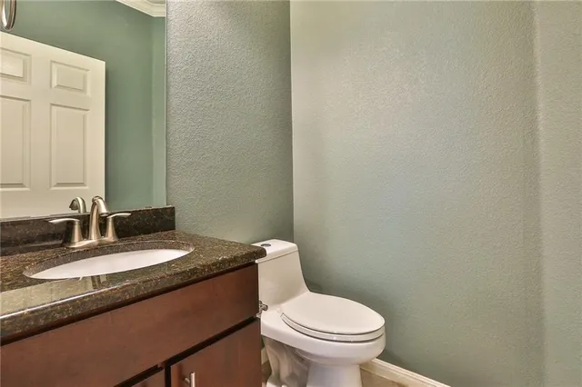 a bathroom with a granite countertop sink a toilet and mirror