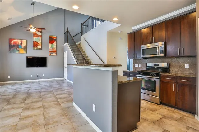a kitchen with stainless steel appliances granite countertop a refrigerator a stove top oven a sink and dishwasher