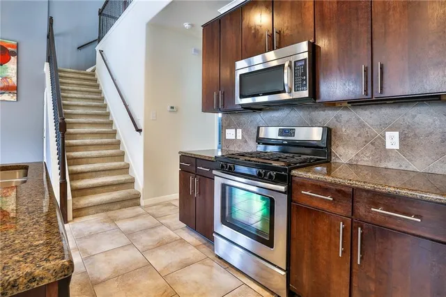 a kitchen with stainless steel appliances granite countertop a stove microwave and sink