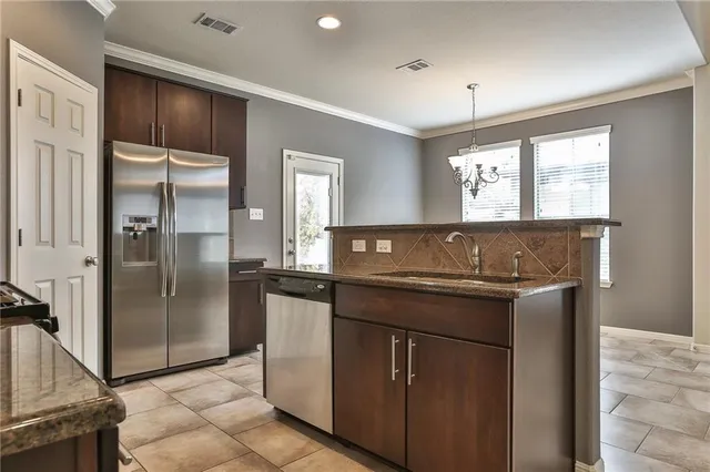 a kitchen with stainless steel appliances granite countertop a sink and a refrigerator