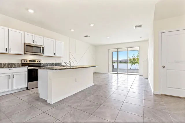 a kitchen with kitchen island granite countertop a stove top oven a sink a counter top space and cabinets