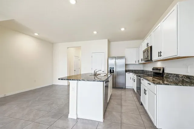 a kitchen with stainless steel appliances granite countertop a stove a sink and white cabinets