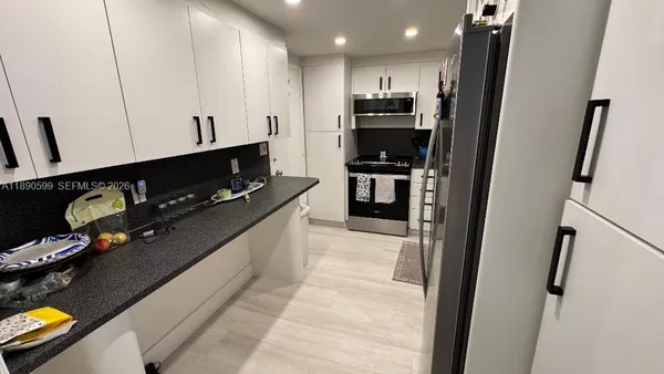 a kitchen with stainless steel appliances kitchen island granite countertop a refrigerator a stove and a sink with wooden floor