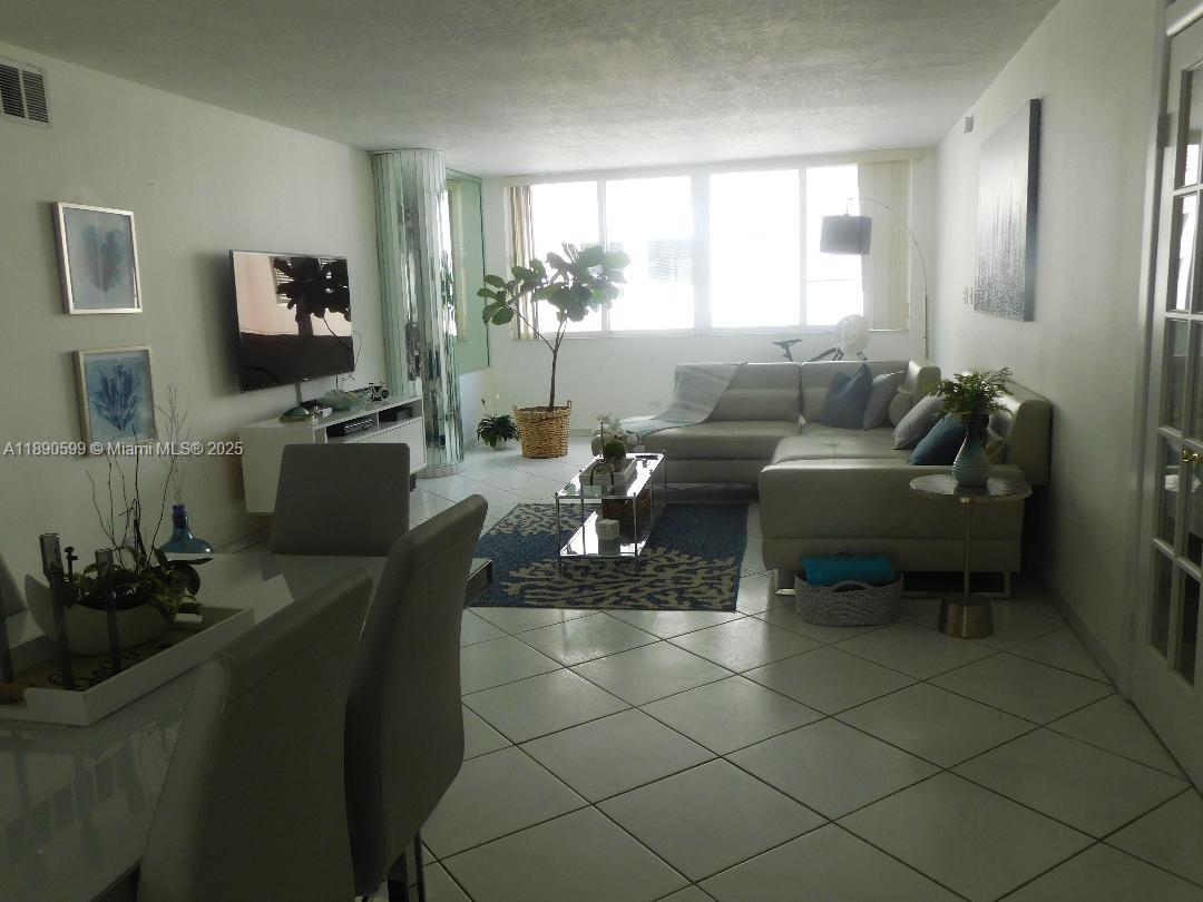 5005 Collins Avenue, Unit 322 Miami Beach, FL 33140 - Photo 6 of 15 a living room with furniture and a flat screen tv