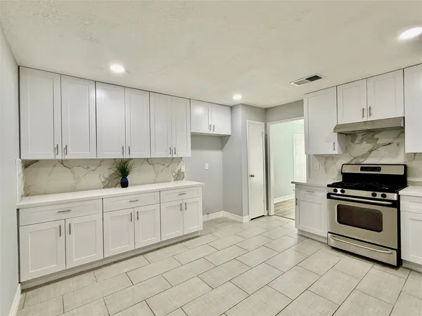 a kitchen with granite countertop white cabinets and stainless steel appliances