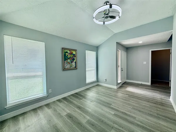 an empty room with wooden floor mirror and windows