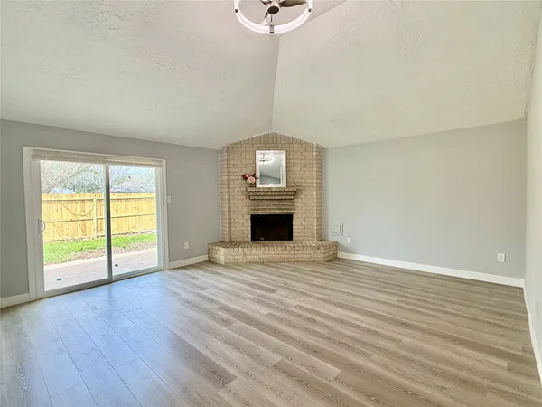 an empty room with wooden floor fireplace and windows