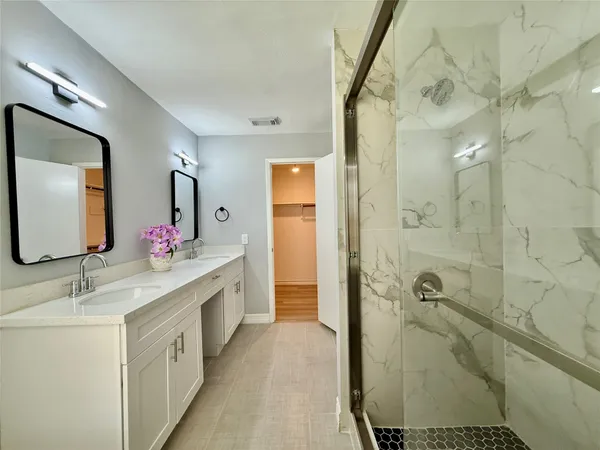 a spacious bathroom with a double vanity sink a mirror and shower