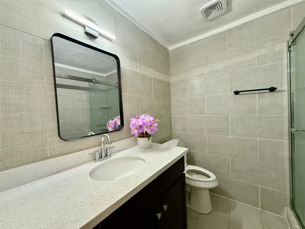 a bathroom with a granite countertop sink a toilet and shower