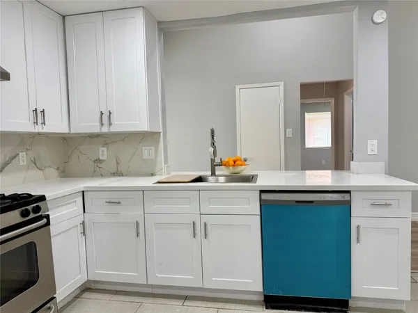 a kitchen with white cabinets and sink