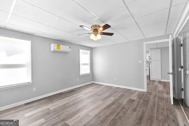a view of empty room with wooden floor and fan