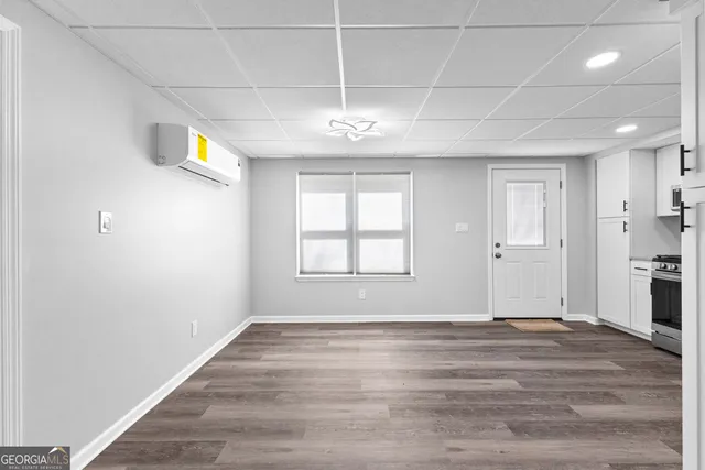 a view of an empty room with wooden floor and a window