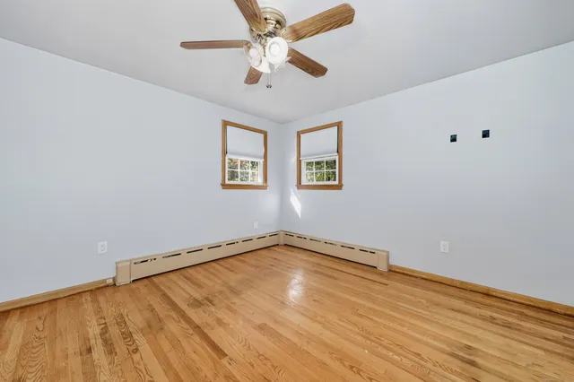an empty room with a ceiling fan and wooden floor