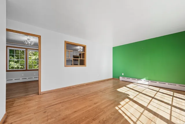 a view of an empty room with window and wooden floor