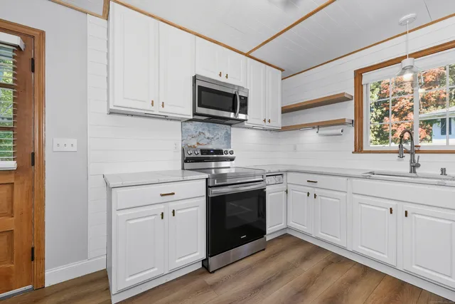 a kitchen with stainless steel appliances granite countertop a sink a stove a microwave and wooden floors