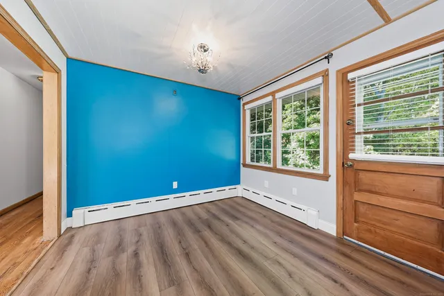 a view of an empty room with a window and wooden floor