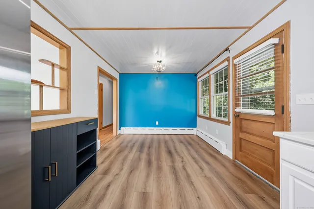a view of an empty room with a window and wooden floor
