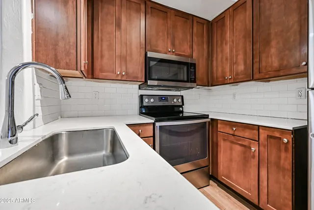 a kitchen with stainless steel appliances granite countertop wooden cabinets a sink and a granite counter top