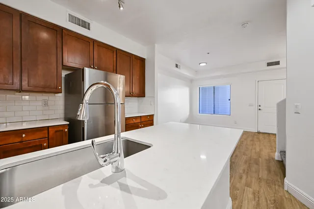 a kitchen with stainless steel appliances kitchen island granite countertop a sink refrigerator and cabinets
