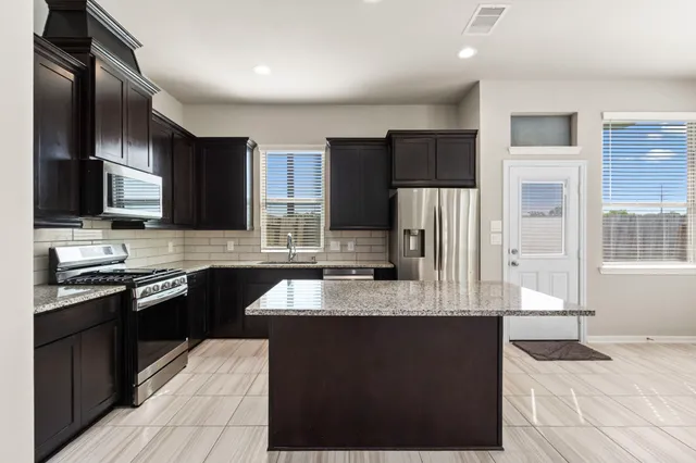 a kitchen with stainless steel appliances granite countertop a refrigerator stove and microwave