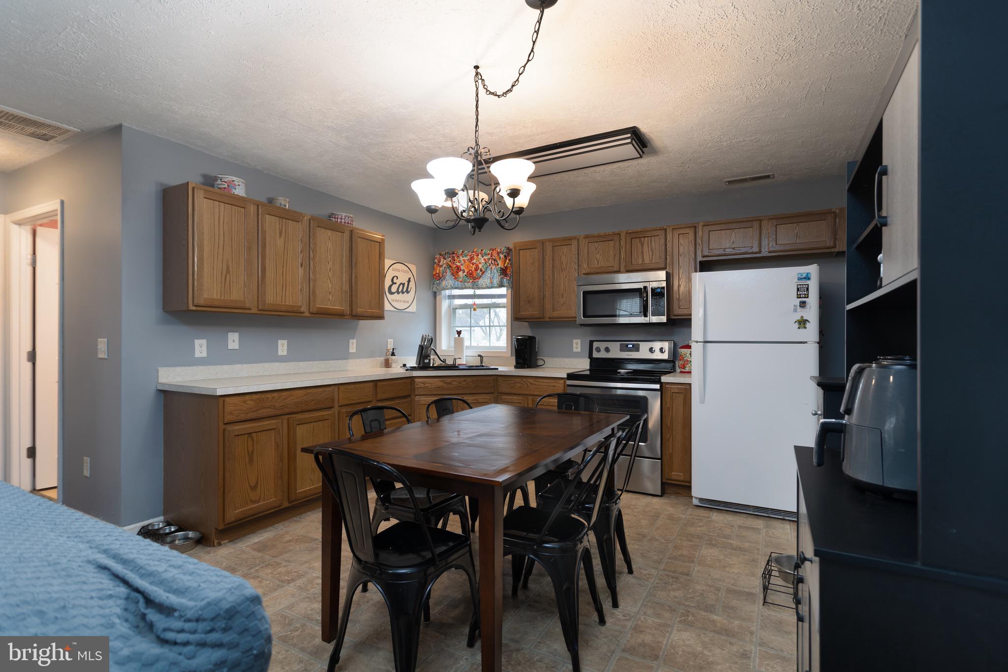 1303 Colonial Avenue Cambridge, MD 21613 - Photo 5 of 12 a kitchen with stainless steel appliances granite countertop a dining table chairs refrigerator and microwave