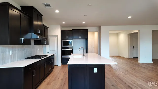 a large kitchen with stainless steel appliances wooden cabinets a stove and a center island