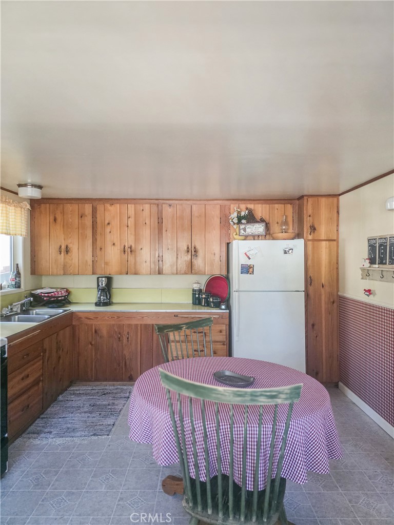 52745 Sylvan Way Idyllwild, CA 92549 - Photo 14 of 31 a kitchen with a white refrigerator a sink dishwasher a dining table and chairs with wooden floor